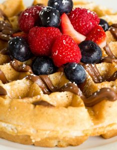 waffle with nutella drizzle and blueberries and strawberries atop